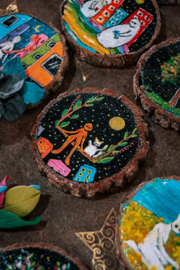 Unique handmade wooden coasters with vibrant, artistic painted designs, showcasing whimsical imagery.